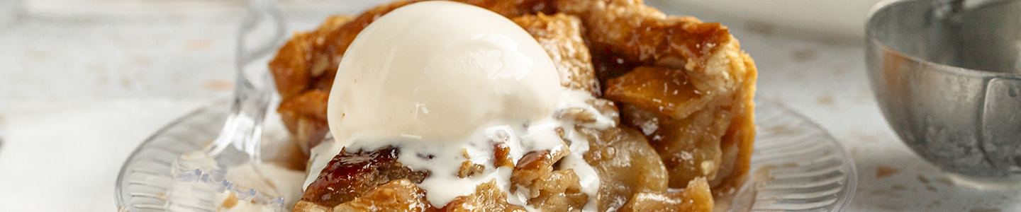 Warm apple pie slice on chinet crystal plate with ice cream ontop