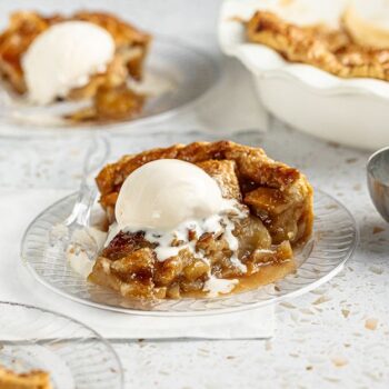 Warm apple pie slice on chinet crystal plate with ice cream ontop