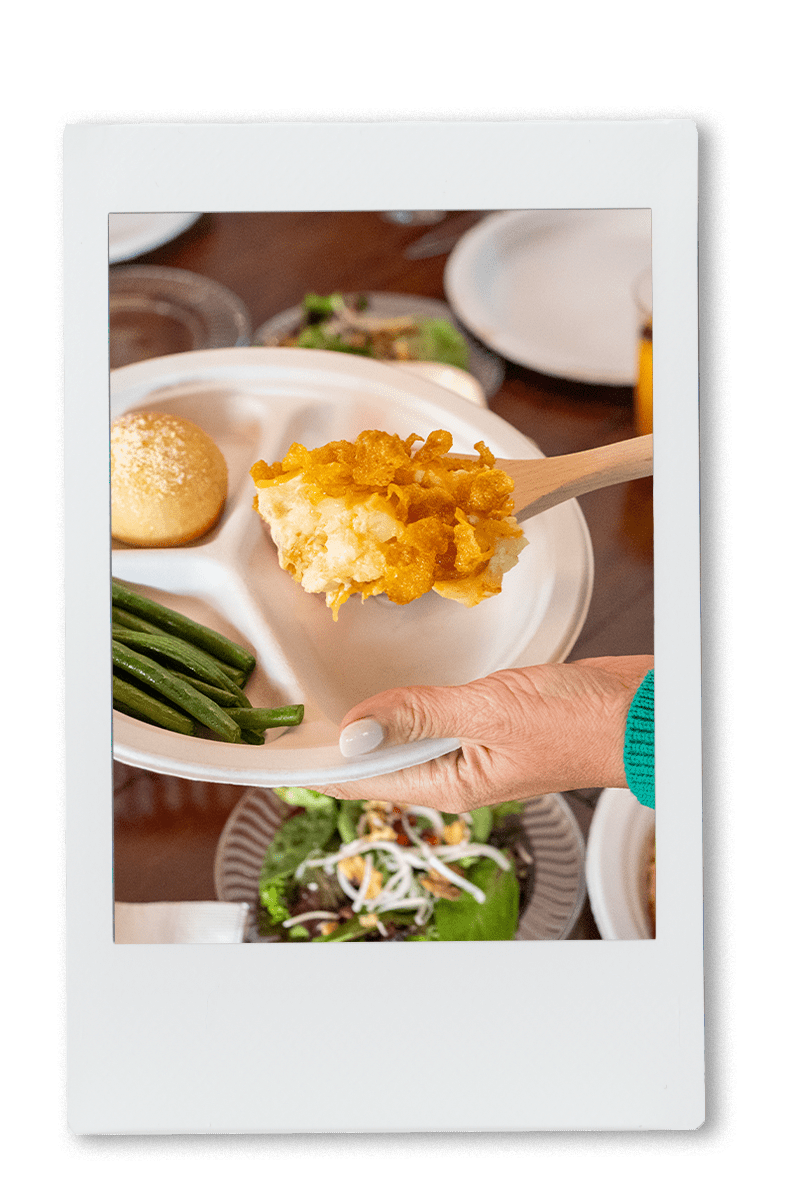 Instax of cheesy potatoes being served on a Chinet plate