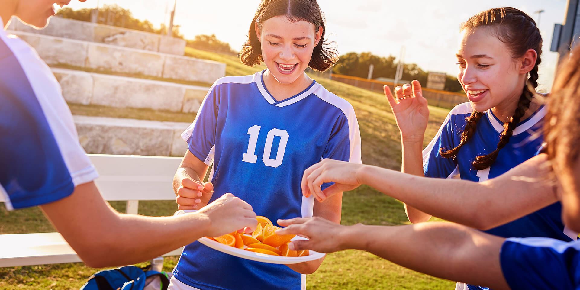 A girls soccer team enjoying a snack break on Chinet® Classic Dinner plates