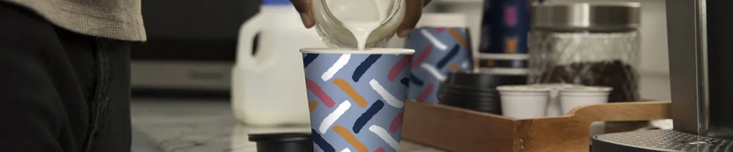 Man pouring frothed milk into a Chinet Comfort cup