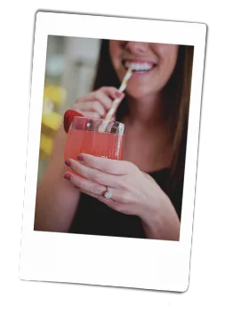 A woman drinking a drink out of Chinet Crystal cup with a straw