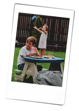 Instax picture of a girl playing with a ball and a boy sitting at a kids' picnic table