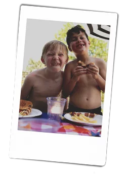 Instax picture of two boys smiling and eating hamburgers