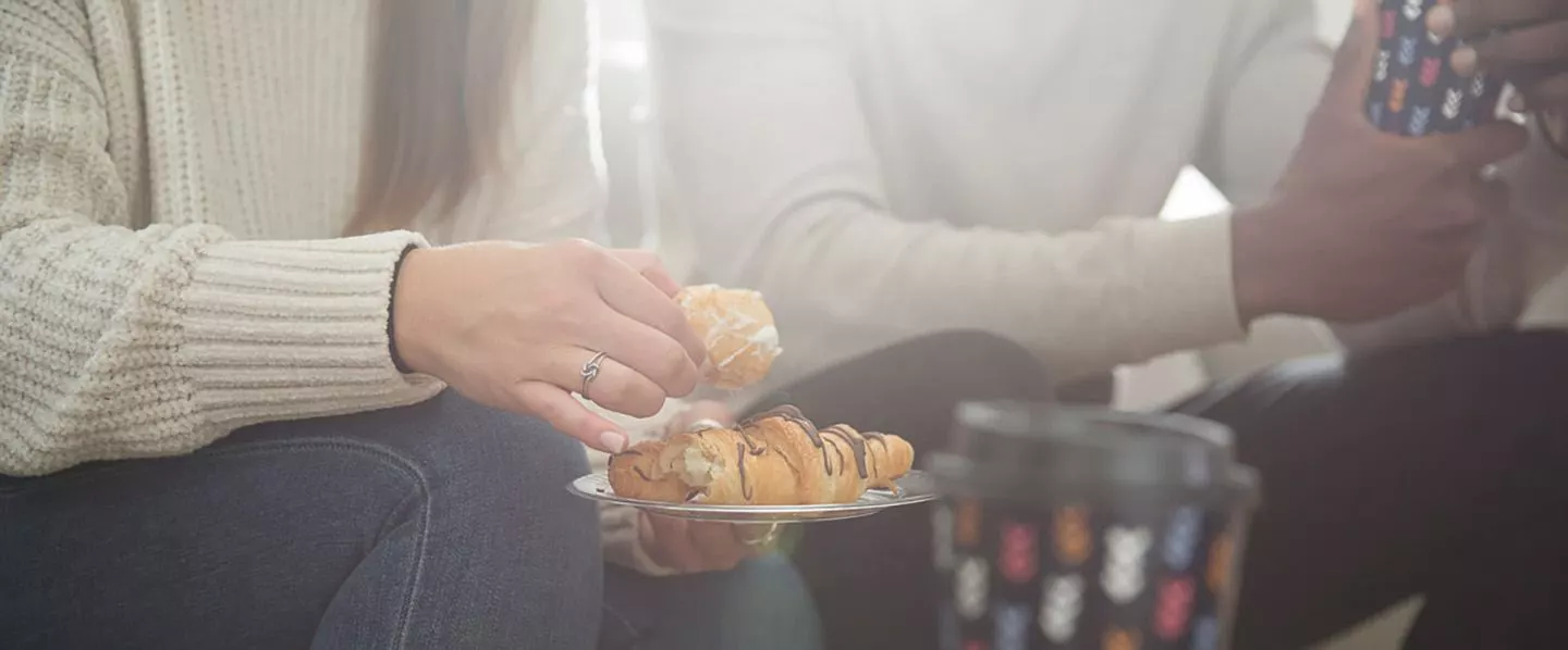 Two people eating pastries and drinking from Chinet Comfort cups