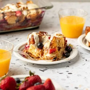 Slice of mixed berry croissant bake served on a Chinet Classic dessert plate next to a Chinet Crystal cup of orange juice