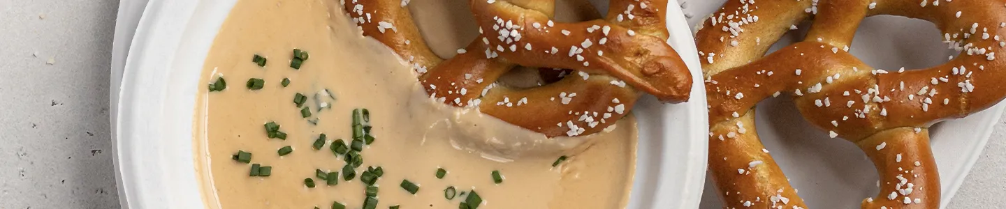 Pretzel be dipping into a bowl of beer cheese dip