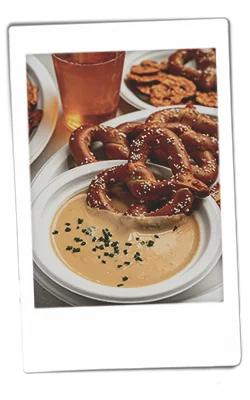 Instax picture of a pretzel be dipping into a bowl of beer cheese dip