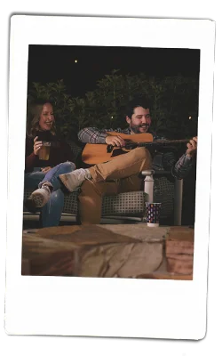 Instax of a man playing guitar by a bonfire with chinet products