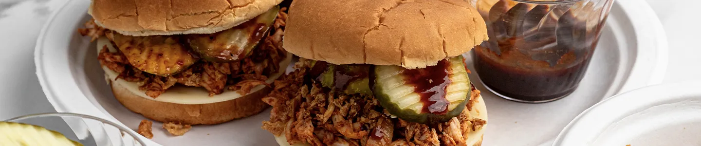 Shredded BBQ chicken sandwiches on a Chinet plate