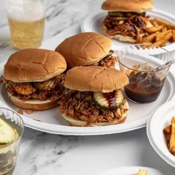 Shredded BBQ chicken sandwiches on a Chinet plate