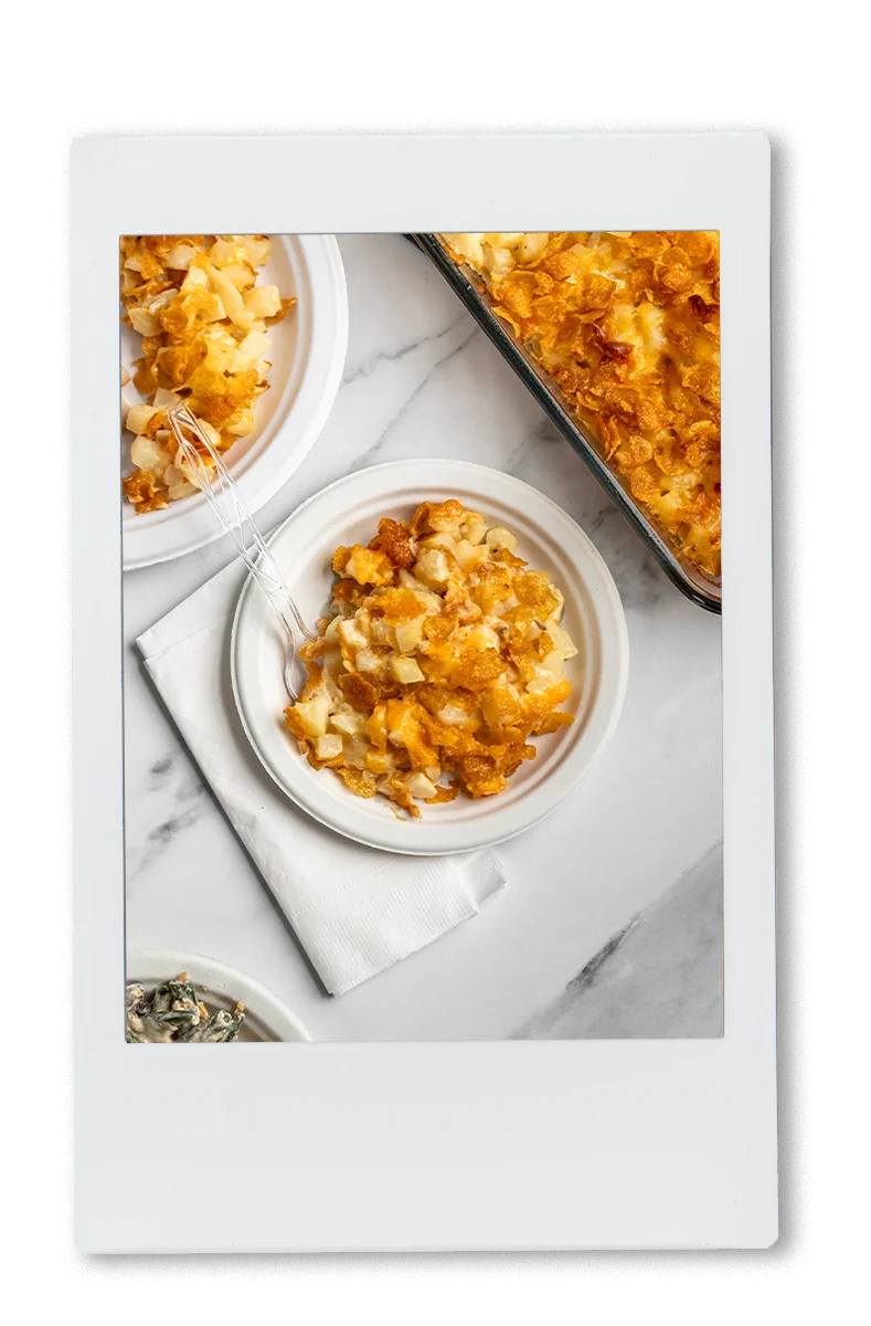 Instax of cheesy potatoes being served on a Chinet plate