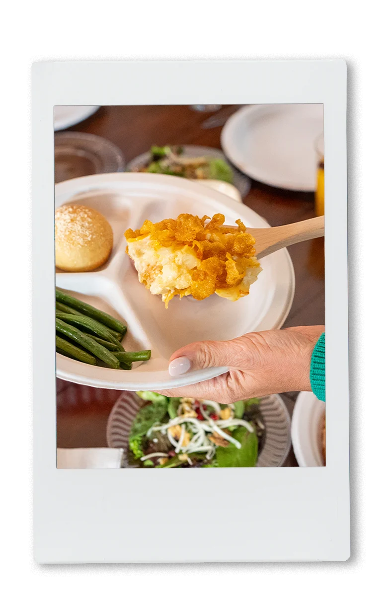 Instax of cheesy potatoes being served on a Chinet plate